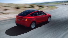 A red 2021 Tesla Model Y driving around a bend