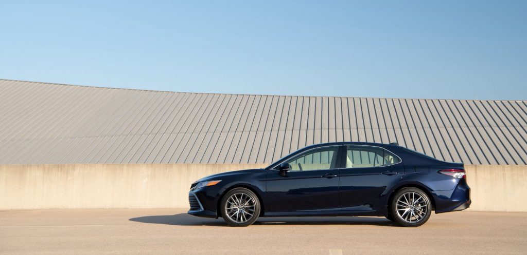 The 2021 Toyota Camry XLE sedan in dark blue parked near a concrete barrier