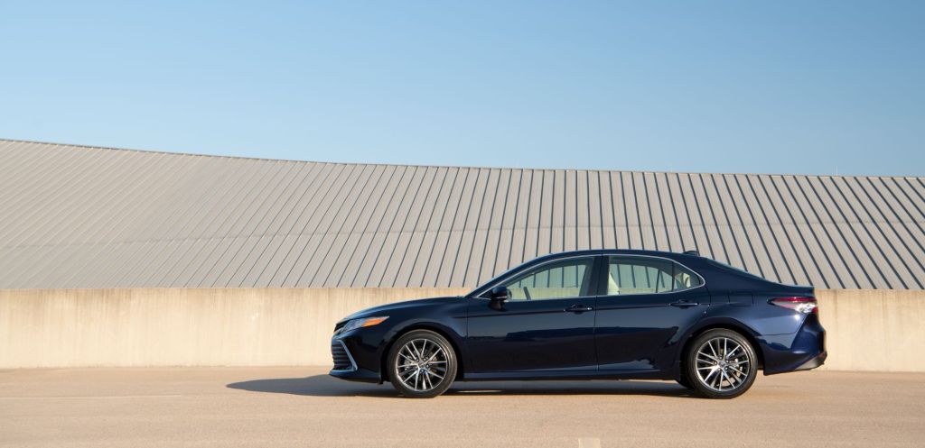 The 2021 Toyota Camry XLE sedan in dark blue parked near a concrete barrier