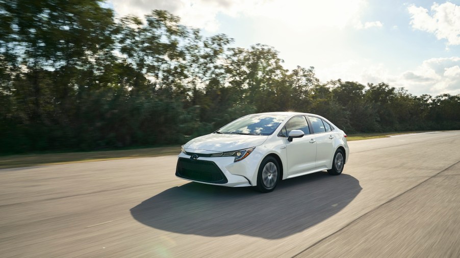 A white 2021 Toyota Corolla Hybrid driving, the 2021 Toyota Corolla Hybrid is a new sedan and is one of the most fuel-efficient new cars