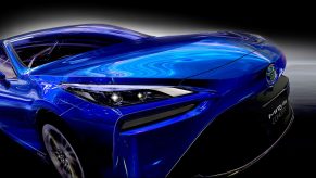 A blue 2021 Toyota Mirai in front of black background with a white glow around the car.