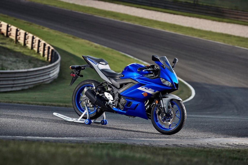 A blue-and-black 2021 Yamaha YZF-R3 sportbike parked on a racetrack on a rear-wheel stand