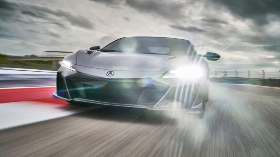 A silver 2022 Acura NSX Type S supercar travels on a racetrack under a cloudy sky