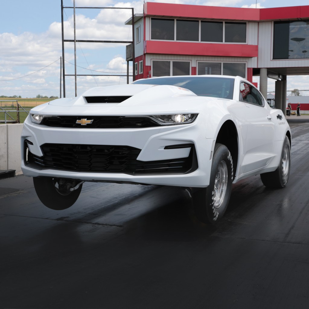 A white 2022 Chevrolet COPO Camaro wheelies down a dragstrip