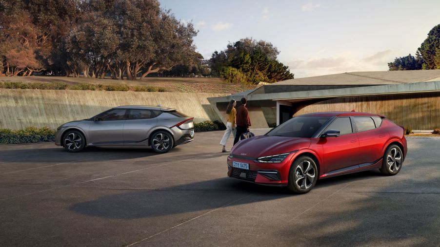 2022 Kia EV6 models in silver and red parked as a couple walks past