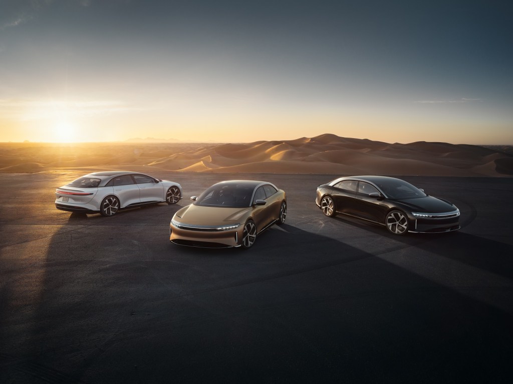 A white, gold, and brown 2022 Lucid Air parked next to a desert