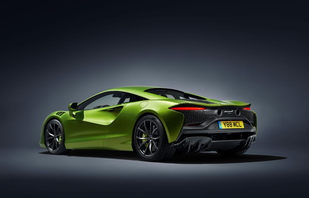 A lime green 2022 McLaren Artura in a black room with a white spotlight on the car.