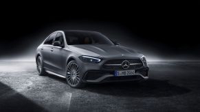 A silver 2022 Mercedes-Benz C-Class on a concrete slab with a black background.