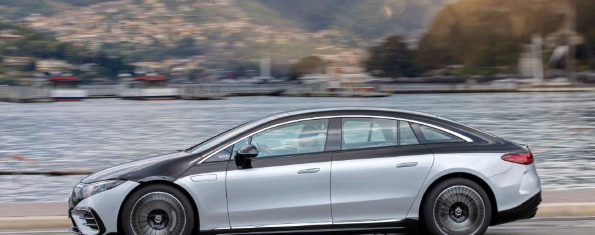 The 2022 Mercedes-Benz EQS electric sedan driving on a highway near docks