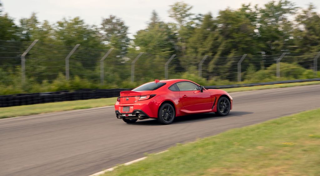 The rear 3/4 view of a red 2022 Toyota GR 86 Premium going around a racetrack corner