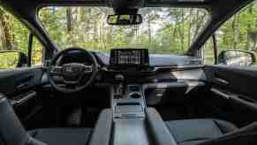 A view of the black front seats, steering wheel, dashboard, and touchscreen of a 2022 Toyota Sienna Woodland Special Edition minivan