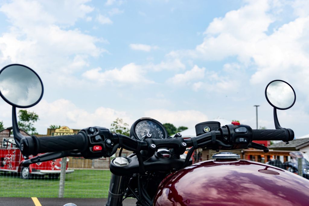 The handlebars and gauge of a red 2022 Triumph Bonneville Bobber