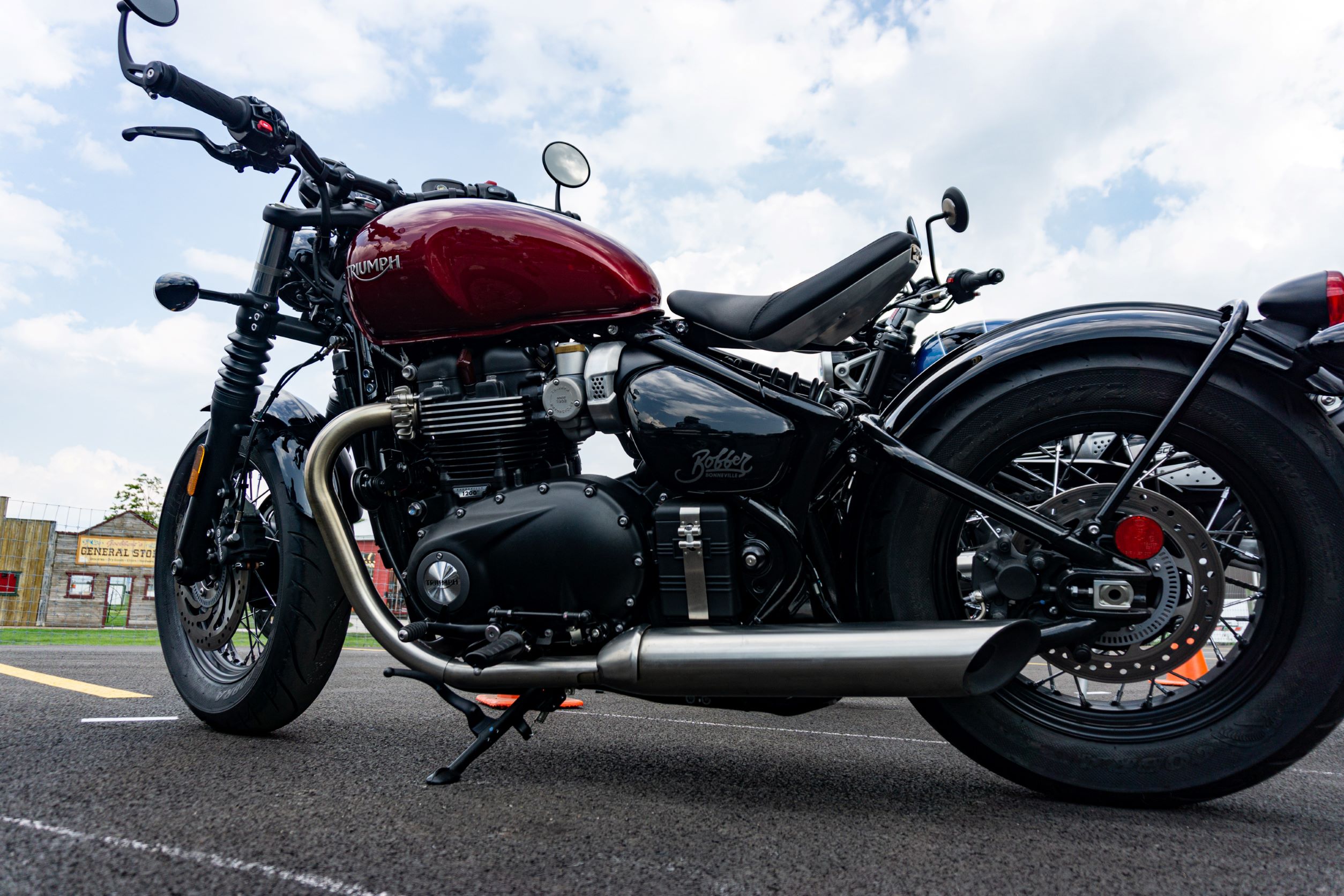 A low-angle view of the left side of a red 2022 Triumph Bonneville Bobber in a parking lot