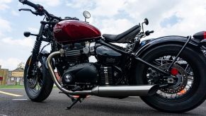 A low-angle view of the left side of a red 2022 Triumph Bonneville Bobber in a parking lot