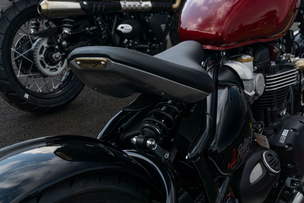 A close-up view of a red 2022 Triumph Bonneville Bobber's seat and rear suspension