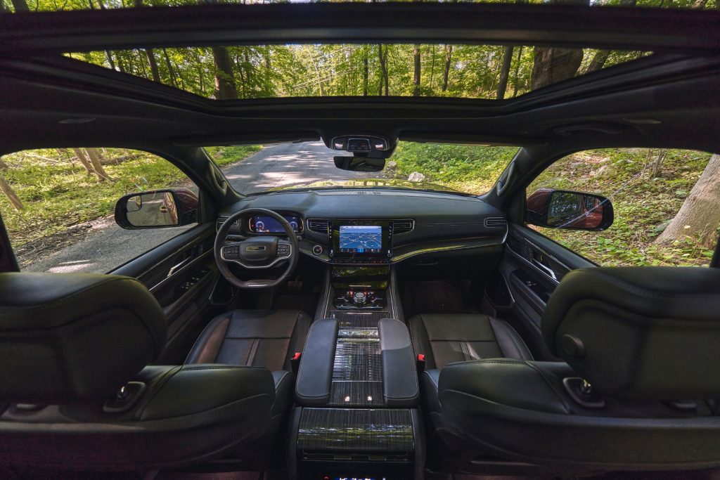 The Nappa-leather-upholstered front seats and dashboard of a 2022 Wagoneer with a sunroof parked in a forest