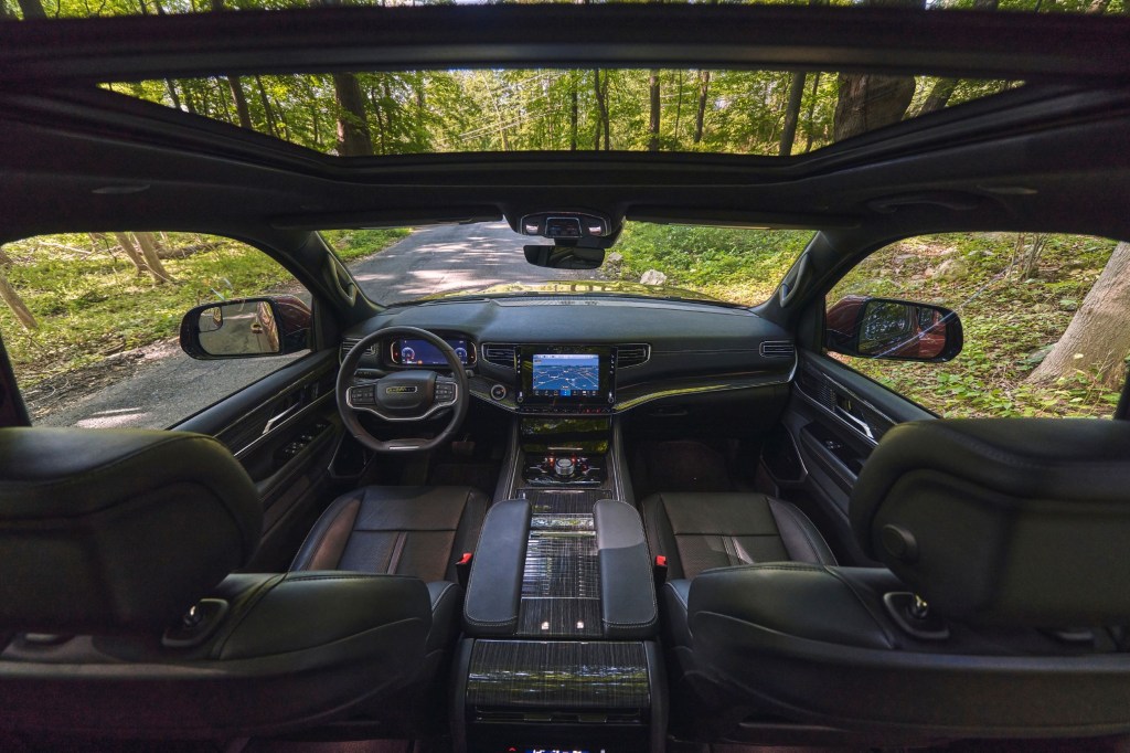 The Nappa-leather-upholstered front seats and dashboard of a 2022 Wagoneer with a sunroof parked in a forest