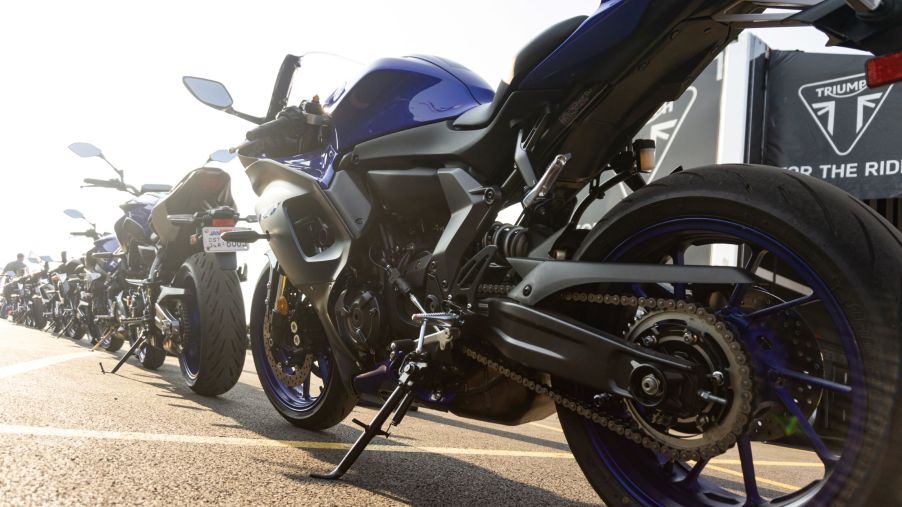 A low-angle rear 3/4 view of a blue-and-black 2022 Yamaha YZF-R7 behind a line of other bikes