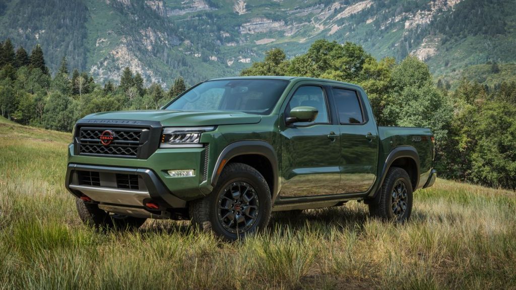 A green 2022 Nissan Frontier parked near the forest