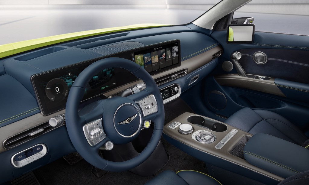 The dark-blue front seats and dashboard of a chartreuse 2023 Genesis GV60 electric crossover SUV
