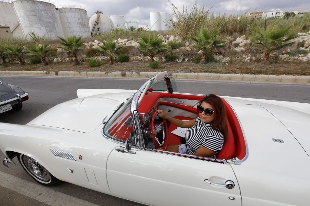 A Lebanese woman drives a white vintage car with a red interior during the 2016 Classic Cars Show in Amchit