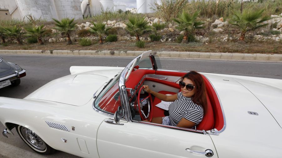 A Lebanese woman drives a white vintage car with a red interior during the 2016 Classic Cars Show in Amchit