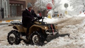 D'Rand Richardson uses a plow-fitted ATV to clear the parking lot in front of a Big Lots store in Louisville, Colorado