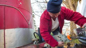 Man is attaching a red box trailer to a ball hitch that is attached to a truck.