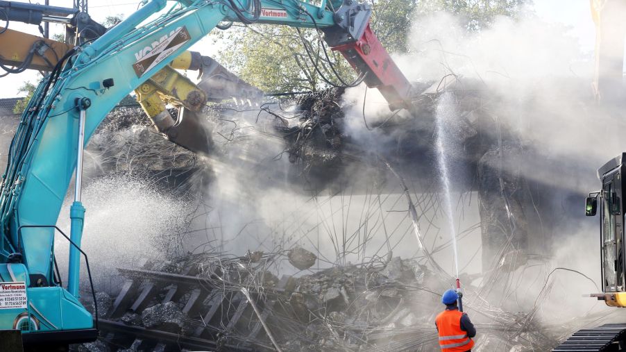 Construction workers tearing down a railway bridge with demolition equipment
