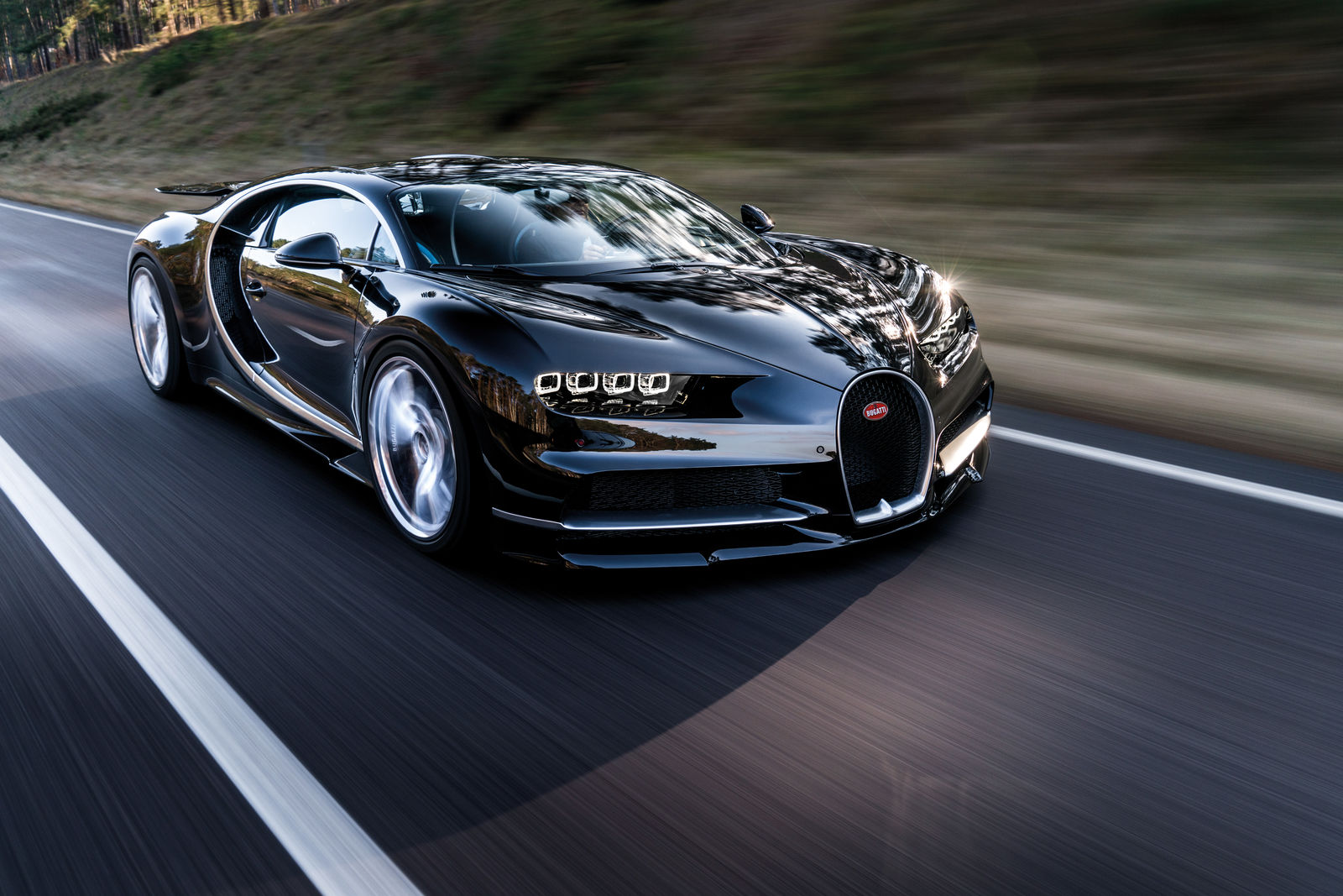 A black Bugatti Chiron supercar travels on a highway