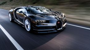 A black Bugatti Chiron supercar travels on a highway