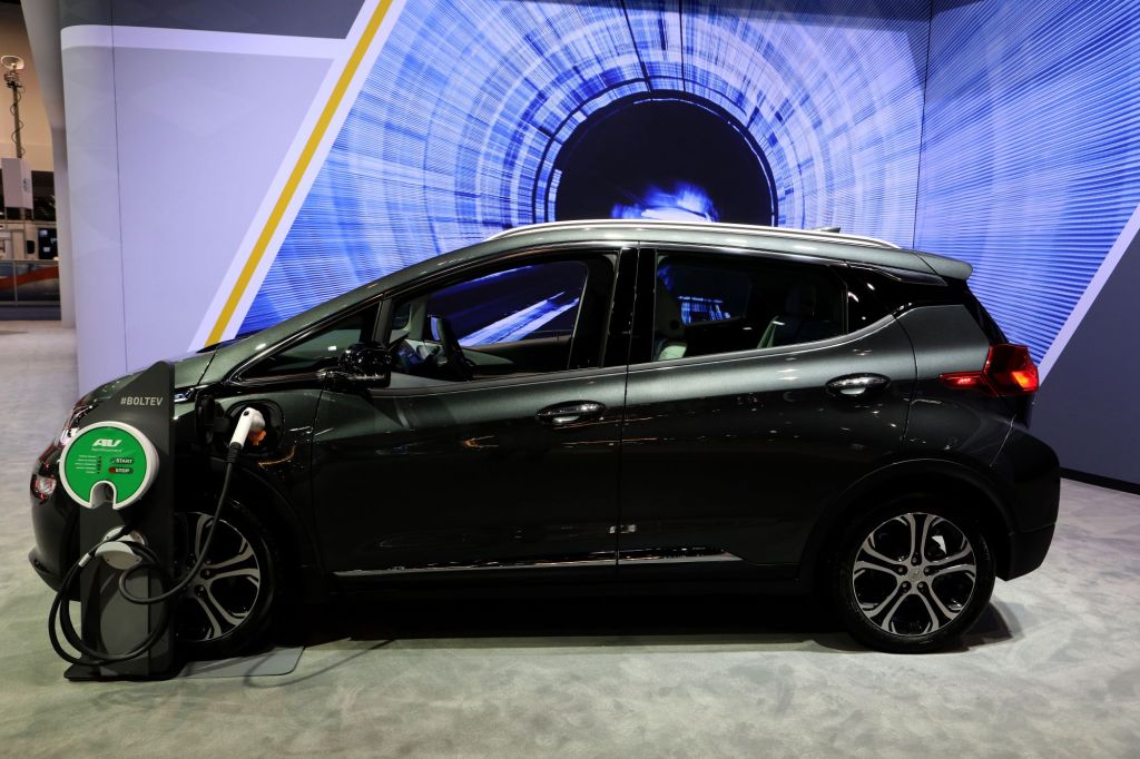 A black Chevy Bolt sits charging in front of a blue and black background.