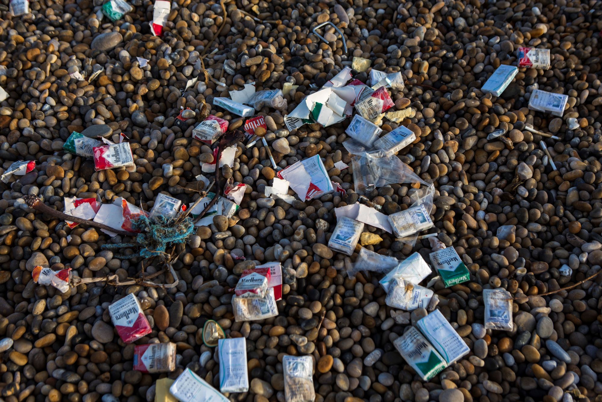 Cigarette packets and other trash washed up on Chesil Beach after a cargo ship accident