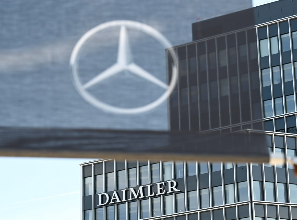 A Daimler logo is attached to a building at the headquarters of the Stuttgart-based car manufacturer, and a flag with a Mercedes-Benz star hangs in the foreground