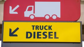 A sign for truck diesel in yellow with black writing with a red sign above that with a white truck and trailer silhouette.
