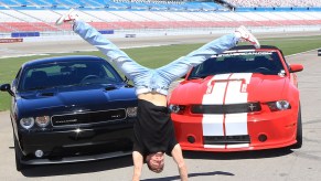 Michal 'Misha Furmanczyk from the show 'Absinthe does a handstand in front of a Dodge Challenger SRT8 392 and a Ford Mustang Shelby GT350 in April 2013 in Las Vegas, Nevada