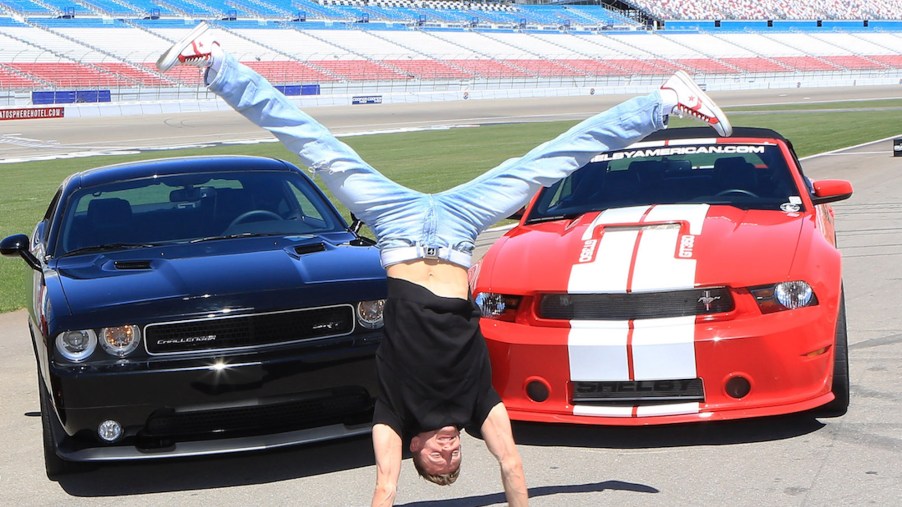 Michal 'Misha Furmanczyk from the show 'Absinthe does a handstand in front of a Dodge Challenger SRT8 392 and a Ford Mustang Shelby GT350 in April 2013 in Las Vegas, Nevada