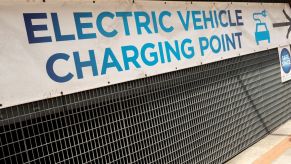 An 'Electric Vehicle Charging Point' sign tied to grating
