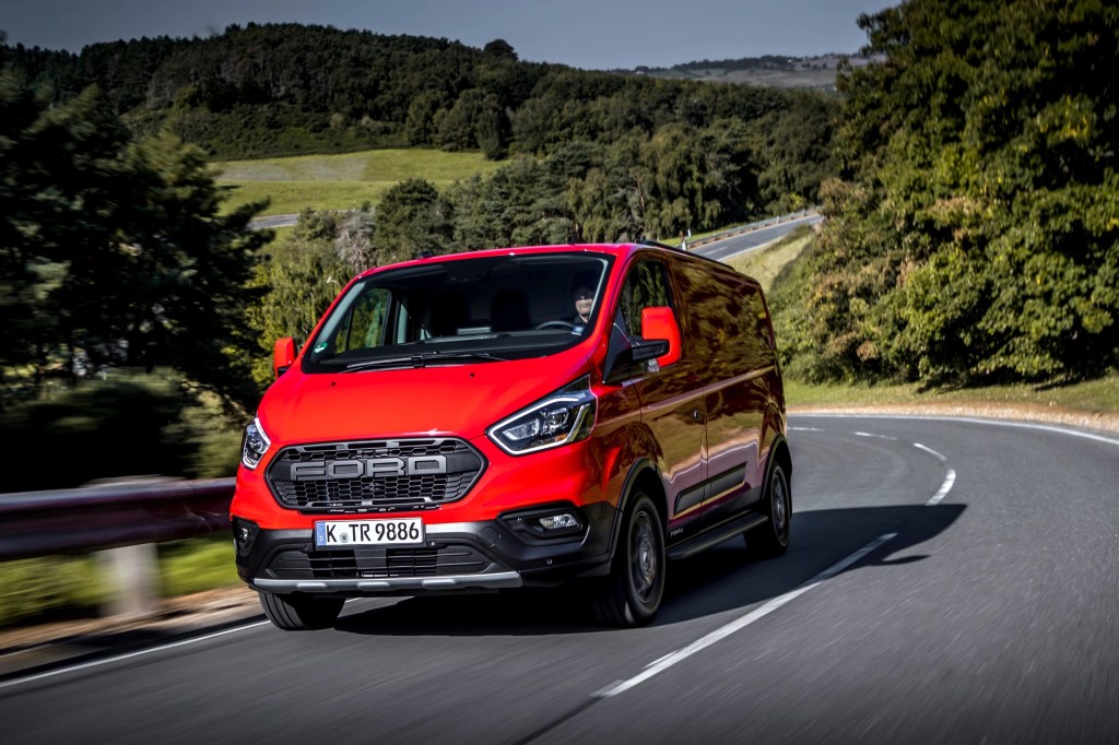 new Ford Nugget Plus Trail camper van in red driving down the road