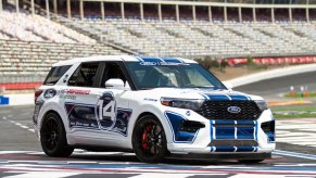 The white-with-blue-stripes Ford Performance Racing School Explorer ST on a racetrack