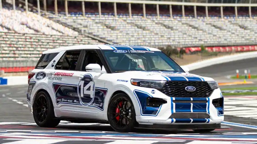 The white-with-blue-stripes Ford Performance Racing School Explorer ST on a racetrack