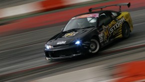 A Nissan S14 drift car siding on track with its headlights on.