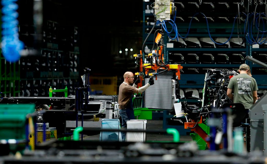 Autoworkers assemble the chassis of full-size pickup trucks at the General Motors plant in Flint, Michigan, in 2019
