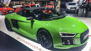 A green Audi R8 V10 Plus Coupe Spyder on display at an indoor auto show.
