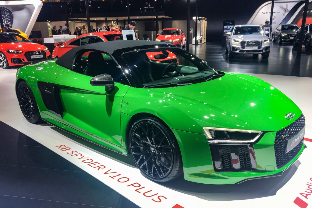 A green Audi R8 V10 Plus Coupe Spyder on display at an indoor auto show. 