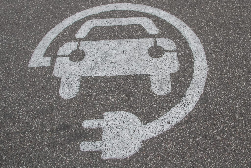 The car-and-charger symbol for EV charging painted onto pavement