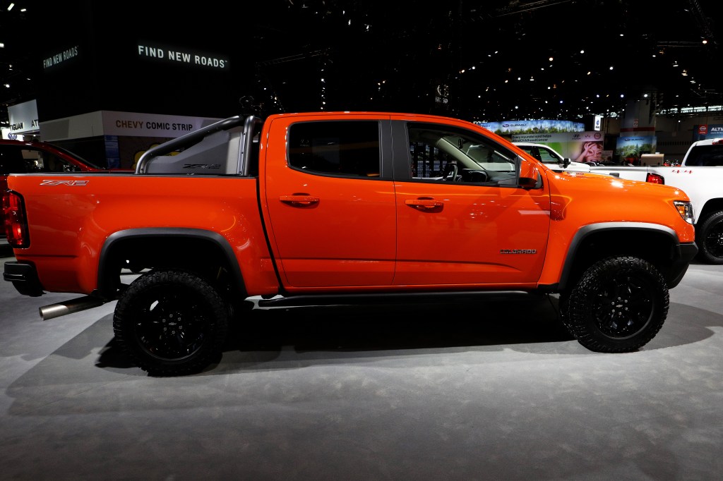 an orange 2021 Chevy Colorado on display at an indoor auto show