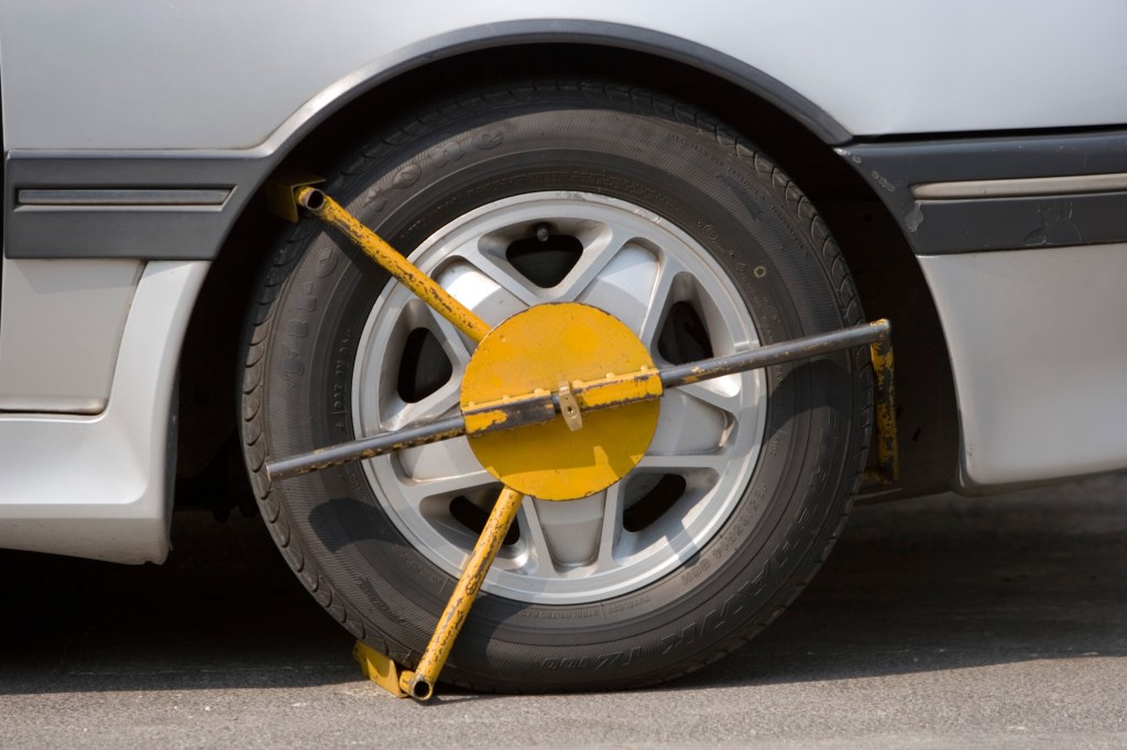 A yellow wheel clamp on a car tire.
