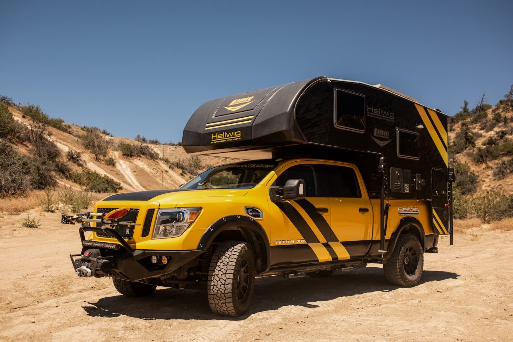 Overland Camping Shelter Options: Mike Hallmark oversaw the creation of the 'Hellwig Rule Breaker' - a 2016 Nissan Titan fitted with a 2017 Lance 650 camper. Mike and his team at Hellwig Suspension Products came up with their unique design for the 2016 SEMA car show. The company's Big Wig airbags in the vehicle's wheel wells allow this one of a kind souped-up pickup to ride level with maximum comfort while navigating any terrain. Mike said: "When you think of a camper you think of a white truck and a white camper, with a white-haired dude driving it at 45 miles-per-hour. We wanted to go the complete opposite, so we did a yellow truck, black camper with some graphics on it to really catch your eye and make a splash in the market." The addition of the Hellwig rear sway bar provides enhanced control while carrying the camper, which features a full audio system, TV, fridge, bed, full-size wet bath, and living area. To accommodate all the added weight, Mike and his team also added Falken Wildpeak AT3W LT 325/65R18 tyres, which beefed-up the truck's on and off-road handling capabilities. Mounted on the front bumper are Baja design lights, fog lights, projection lights, and a full light bar that allows the driver visibility while traveling at night or off-roading. The whole thing is powered by a Cummins 5.0L V8 turbo diesel engine.