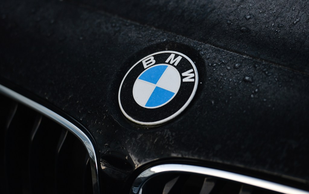 BMW's logo seen on the hood of a black vehicle in the rain